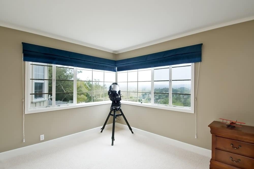 Room with large corner windows and a telescope stored ready for use