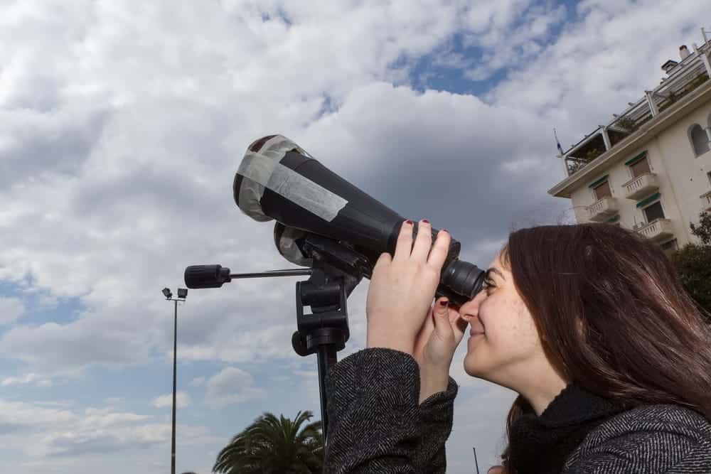 woman Looking through binoculars to observe the Sun