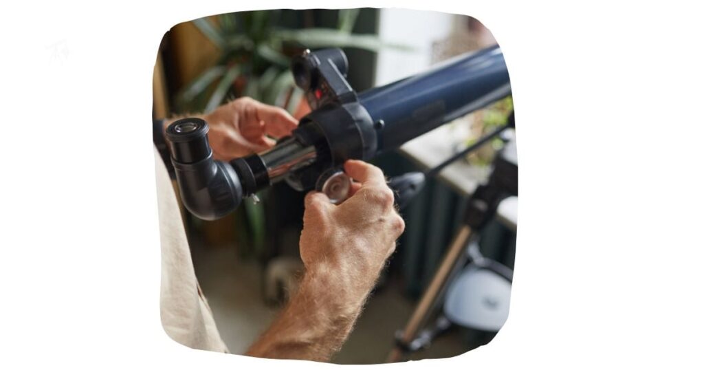 man adjusting the focus on a telescope