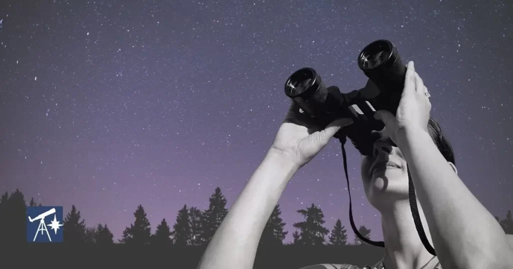 person looking up at night sky with set of binoculars